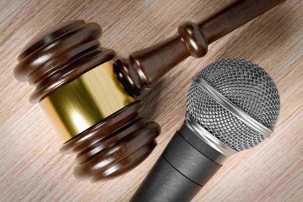 Close-up of a gavel next to a silver microphone, symbolizing media law or courtroom statements.
